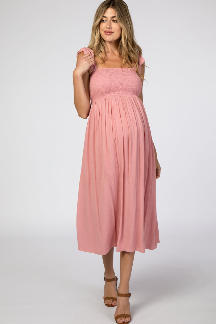 woman wearing a pink smocked maternity dress with ruffled straps and a visible baby bump
