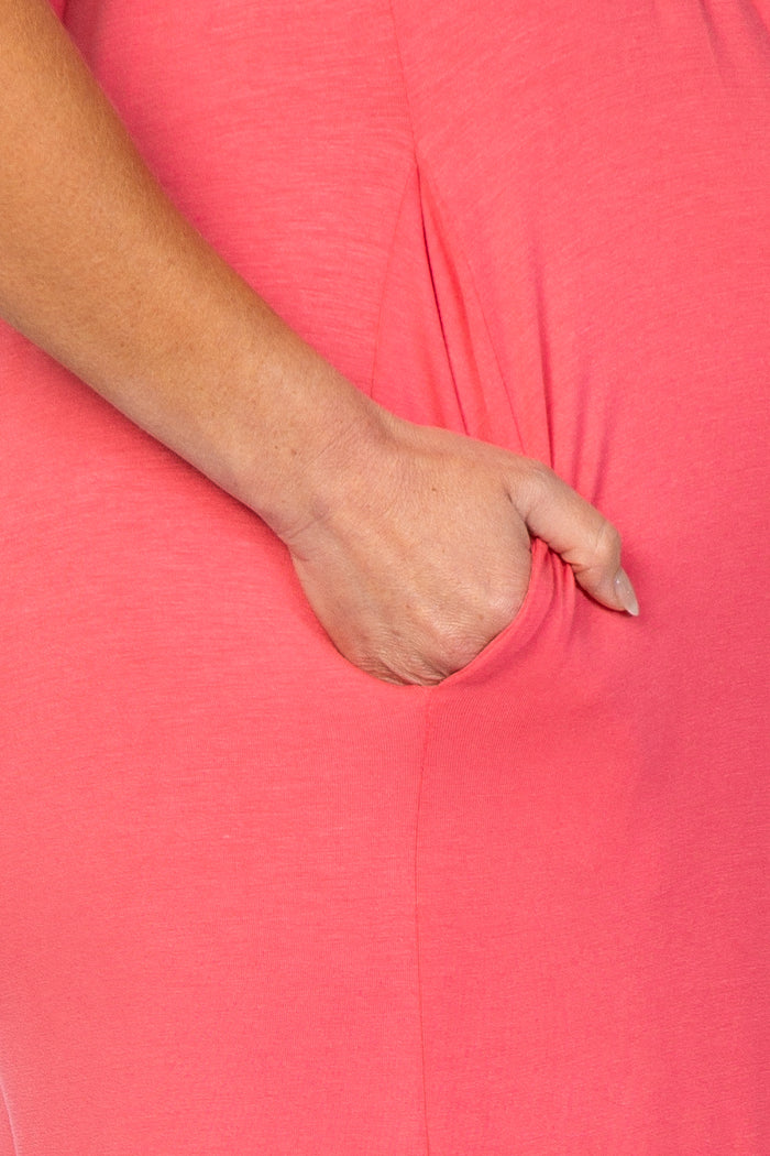close-up of a pregnant belly in a coral maternity dress with a side pocket