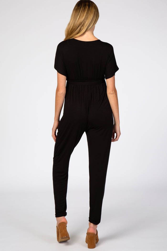 woman wearing a black maternity jumpsuit with short sleeves and a relaxed fit from the back