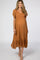 woman wearing a rust-colored maternity dress with flutter sleeves and a ruffled hem, showcasing her baby bump