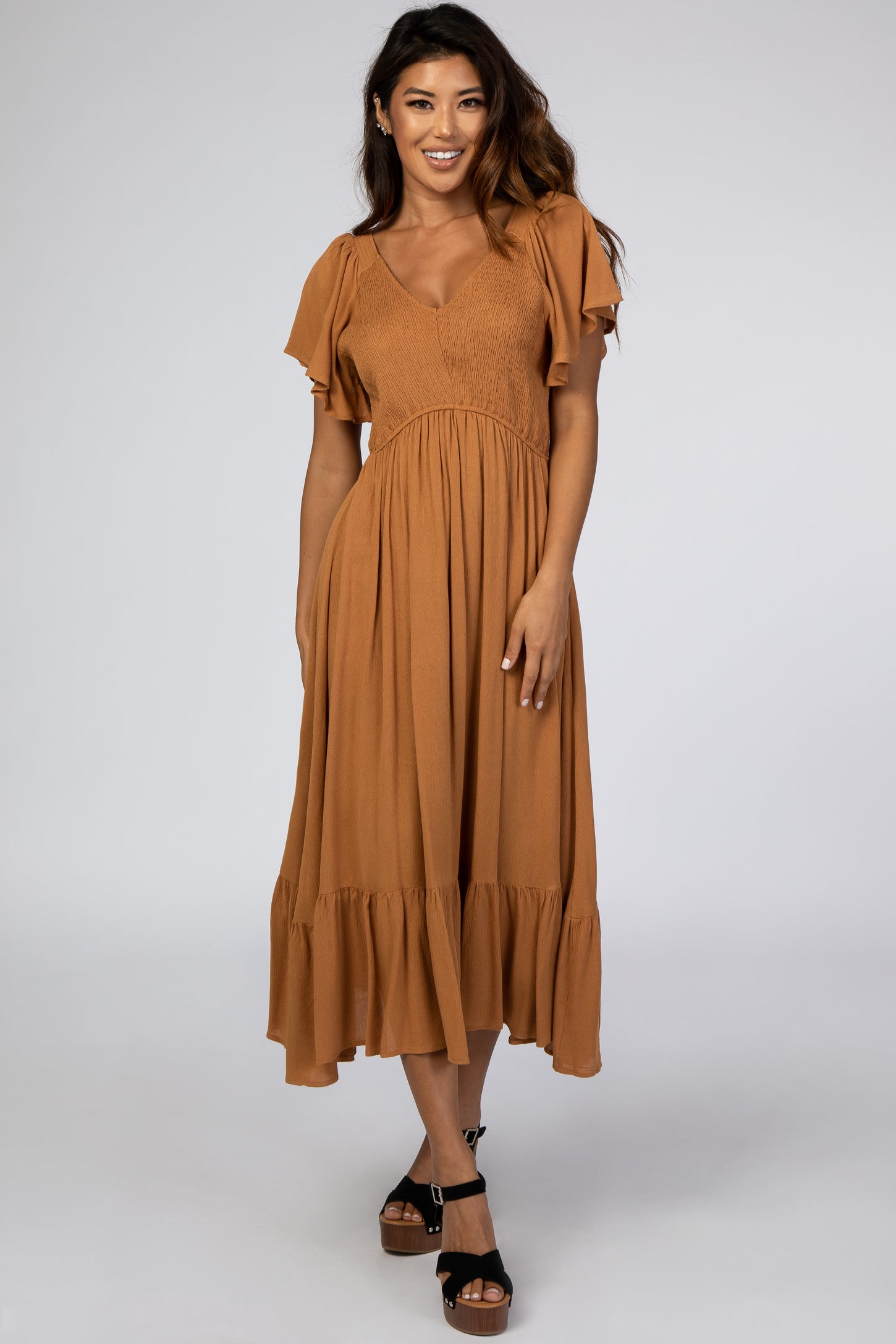woman wearing a rust-colored midi dress with ruffle sleeves and a tiered hem