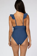 woman wearing a navy blue one-piece swimsuit with ruffle straps and a low back