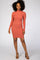 woman wearing a fitted rust-colored long sleeve dress with a mock neck and a slim silhouette