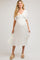 woman wearing a white maternity dress with a v-neck and flutter sleeves, holding her baby bump