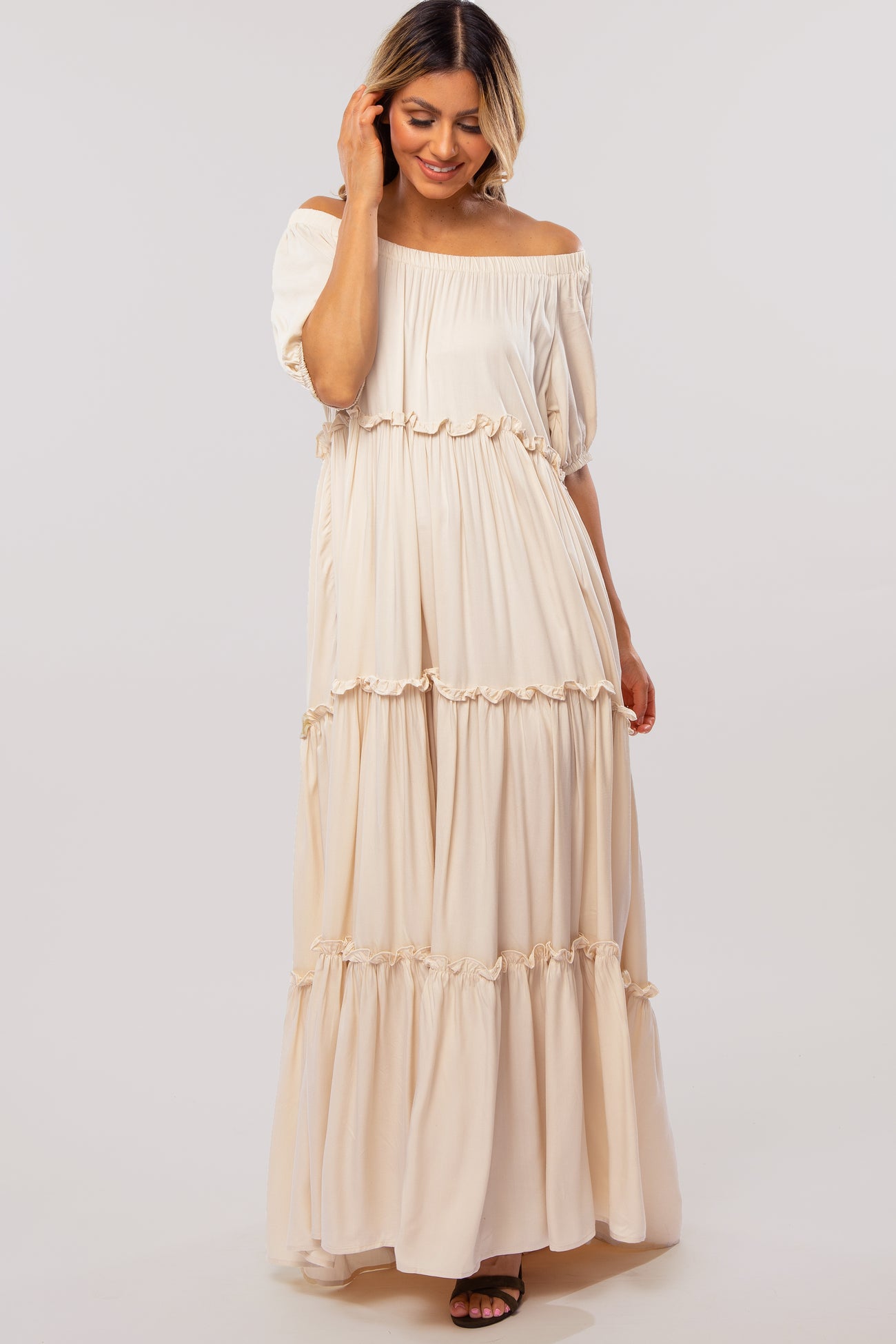 woman wearing a beige off-the-shoulder tiered maxi dress with ruffle details and short puff sleeves