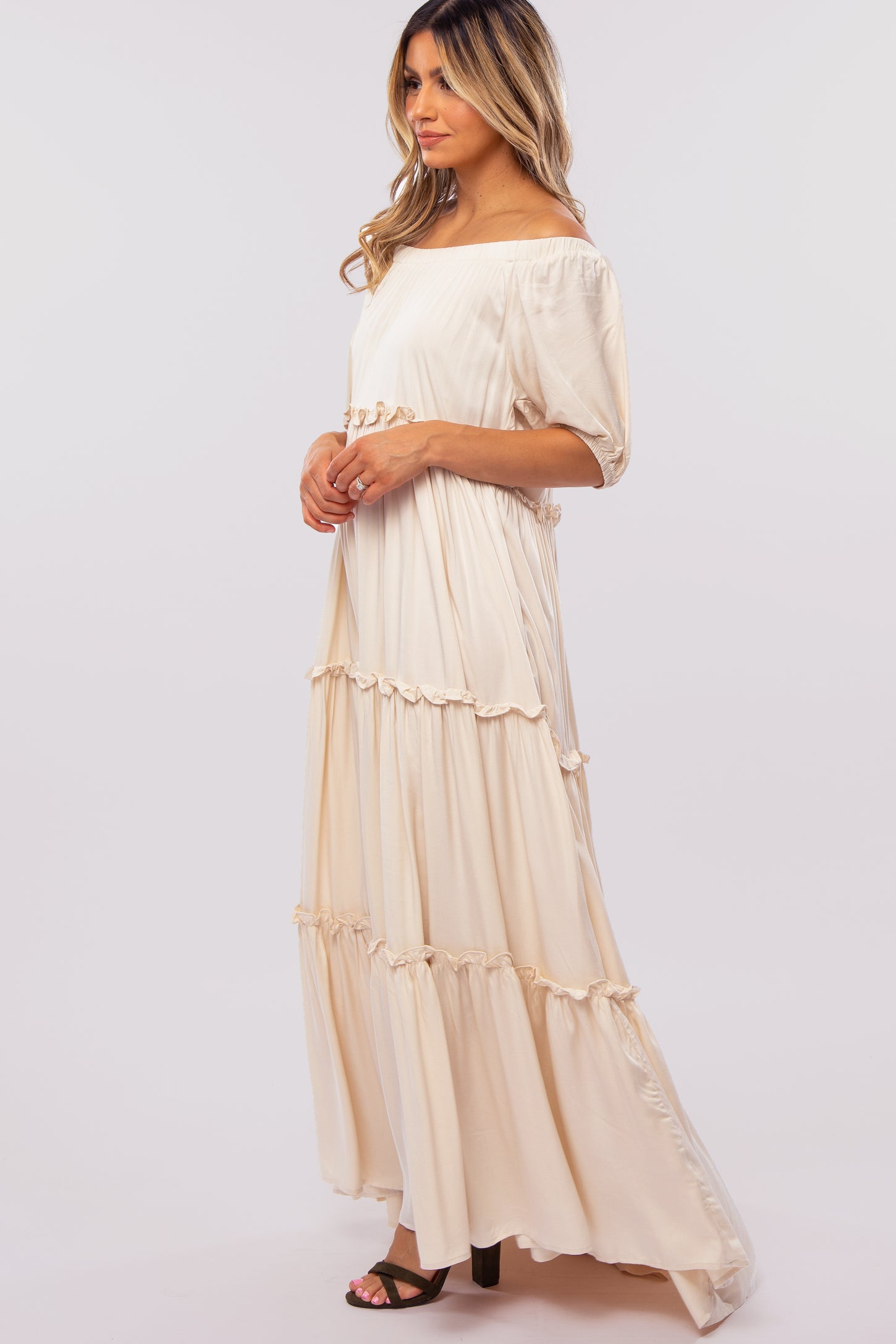 woman wearing a cream off-the-shoulder maxi dress with ruffle detailing and short sleeves