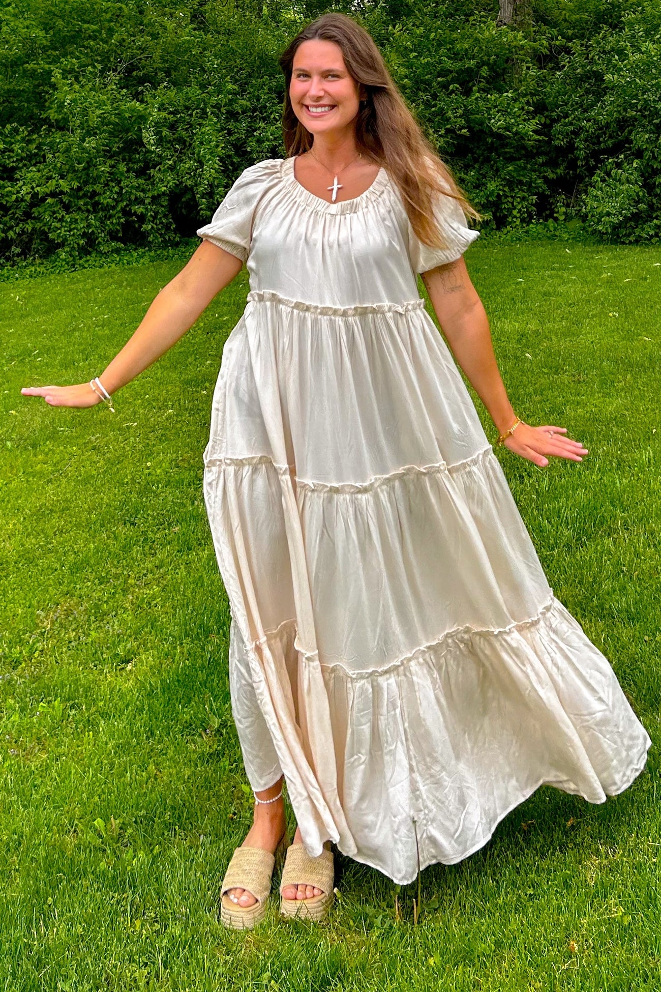 woman wearing a cream tiered maxi dress with short sleeves and a relaxed fit standing on grass