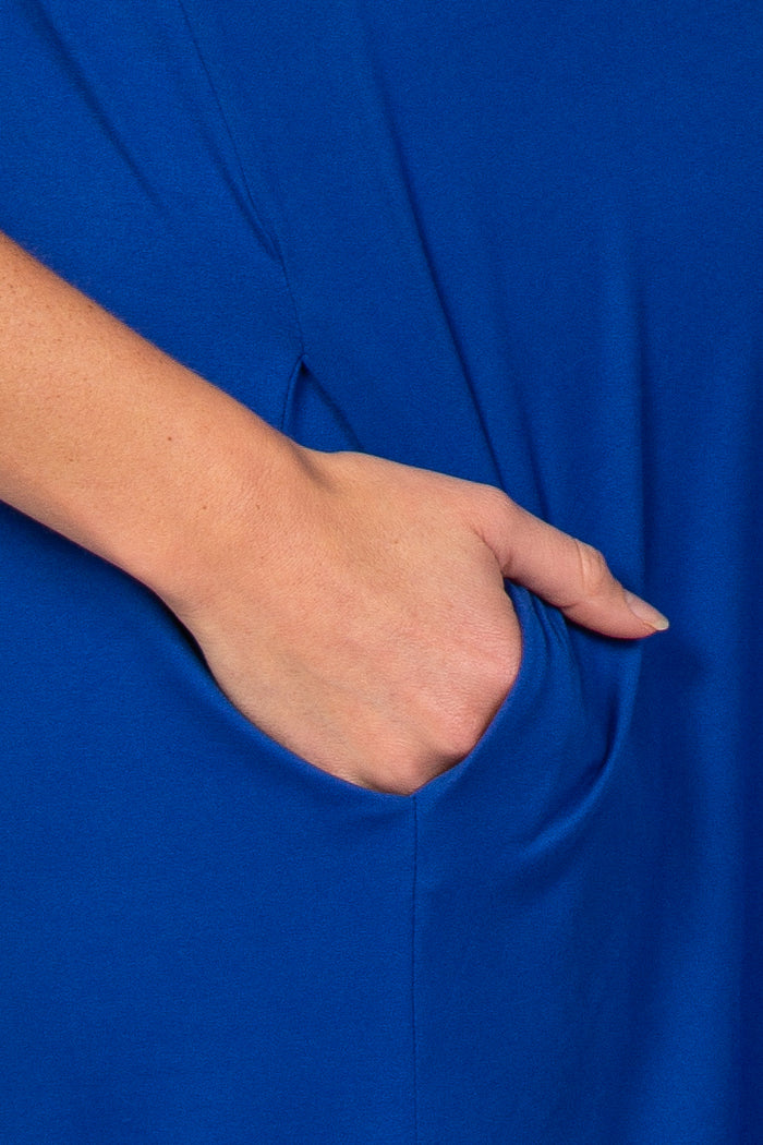 close-up of a hand in the pocket of a bright blue maternity top