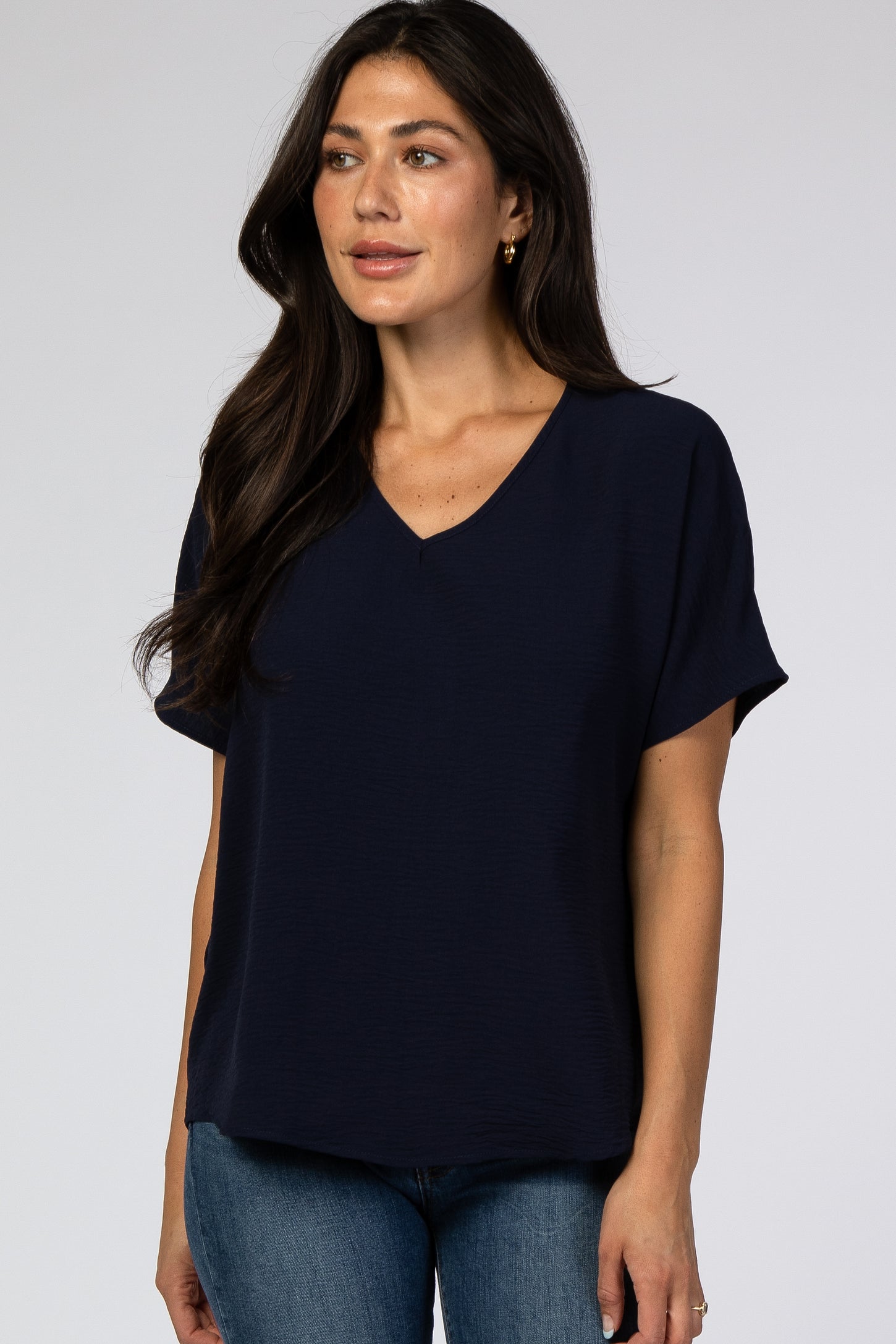 woman wearing a navy blue short sleeve v-neck top paired with blue jeans