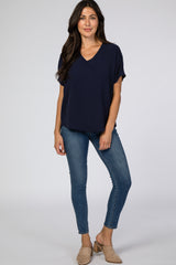 woman wearing a navy blue short sleeve v-neck top with jeans and beige mules