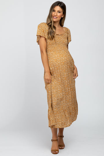 woman wearing a mustard yellow floral maternity maxi dress with short sleeves and a ruched bodice, showing her baby bump