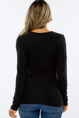 woman wearing a fitted black long sleeve top, shown from the back, paired with blue jeans