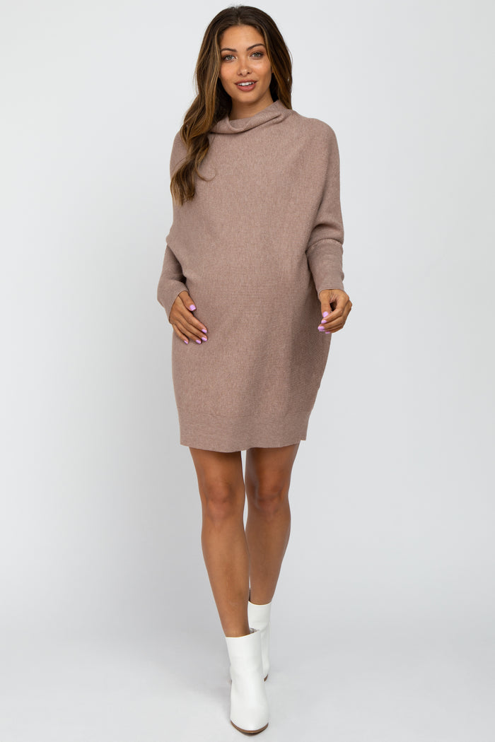 woman wearing a taupe oversized maternity sweater dress and holding her baby bump