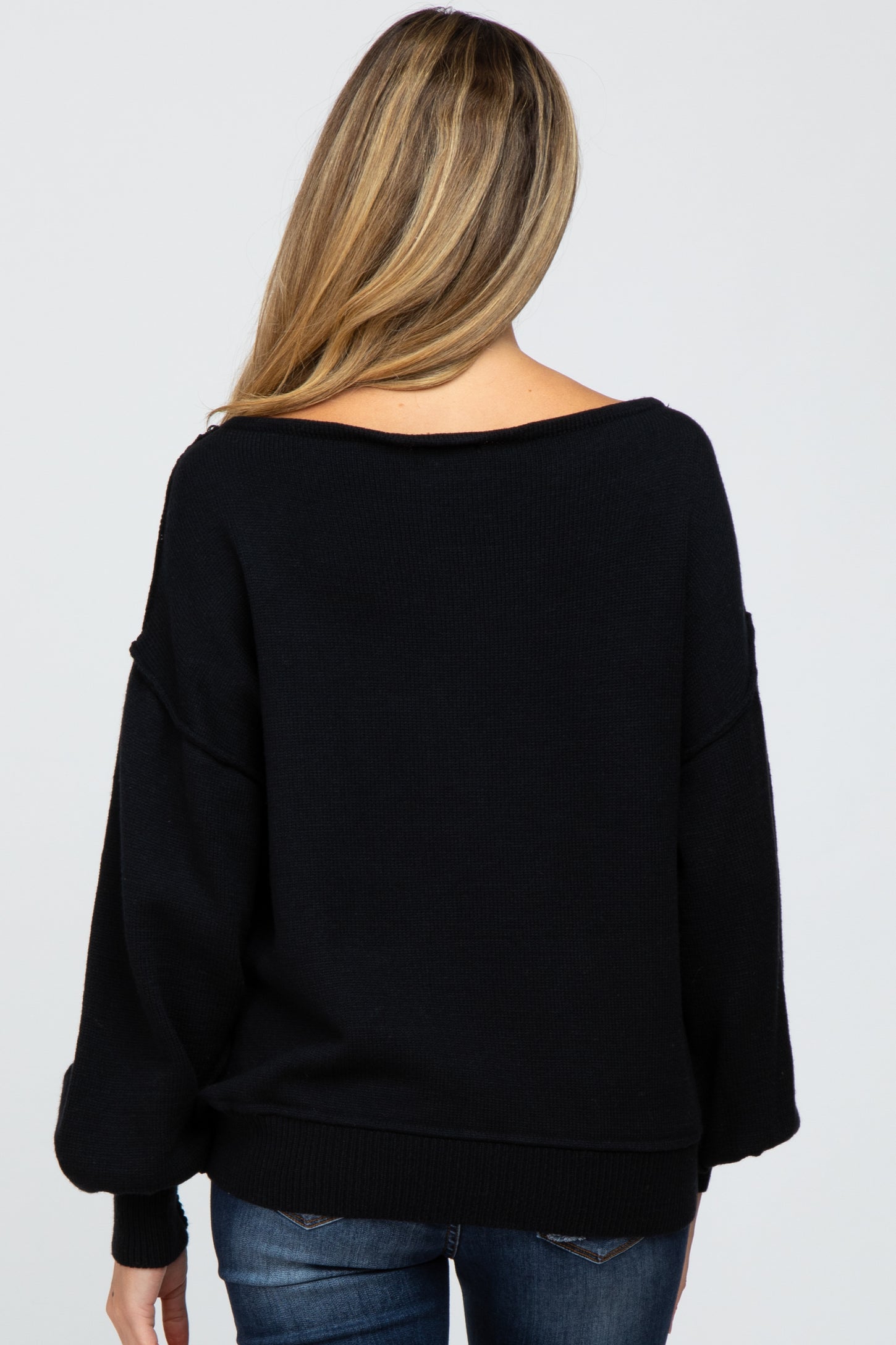 woman wearing a black oversized maternity sweater, showing a relaxed fit and wider neckline from the back