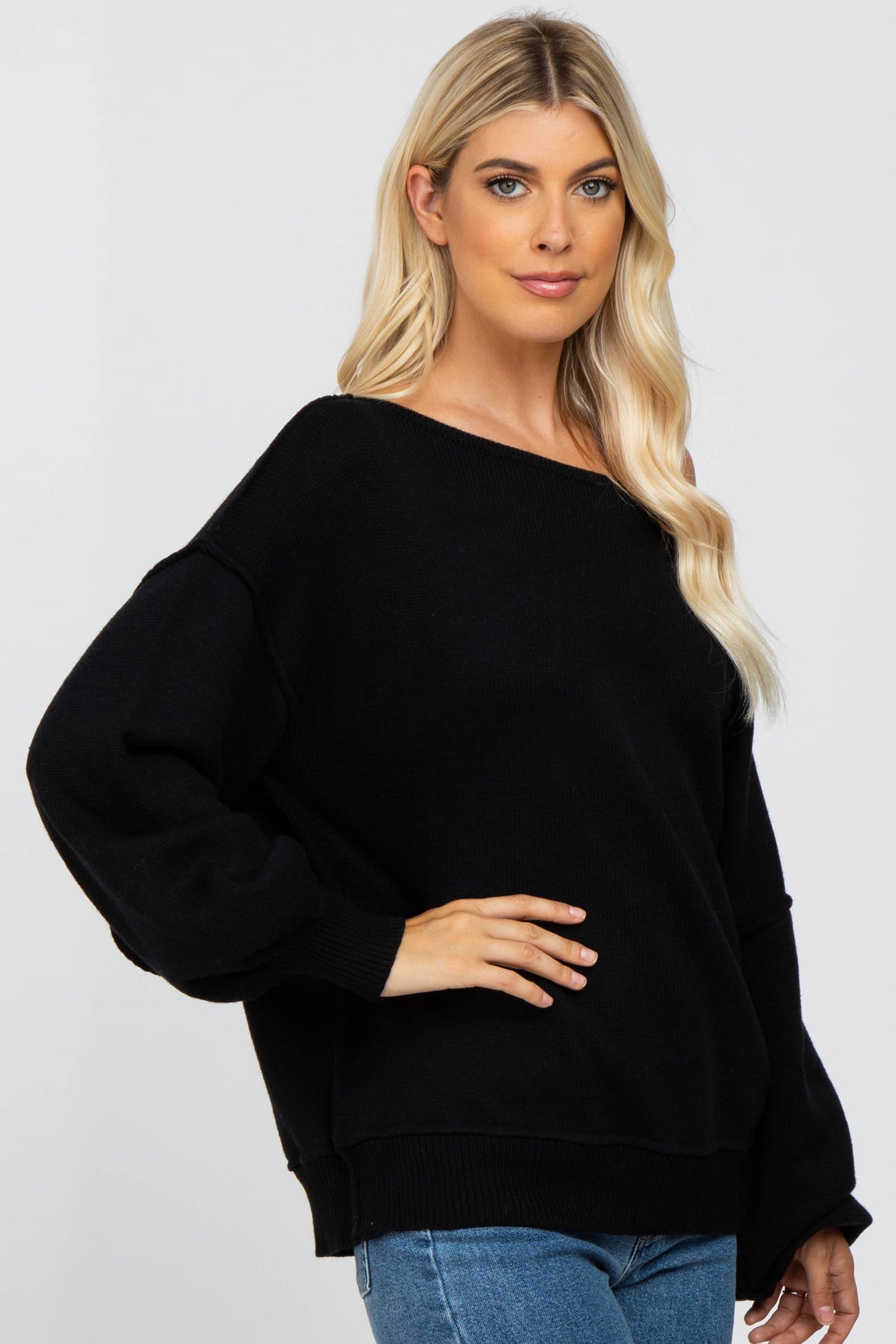 woman wearing an oversized black off-shoulder sweater with long sleeves and a relaxed fit