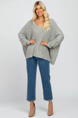 woman wearing oversized grey knit sweater and blue straight leg jeans with tan ankle boots