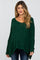 woman wearing a dark green sparkly maternity sweater with a relaxed fit and wide sleeves