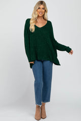 woman wearing a green sparkly oversized sweater with a v-neck and blue high-waisted jeans