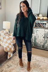woman wearing a dark green oversized knitted sweater with a hood, black ripped skinny jeans, and brown ankle boots