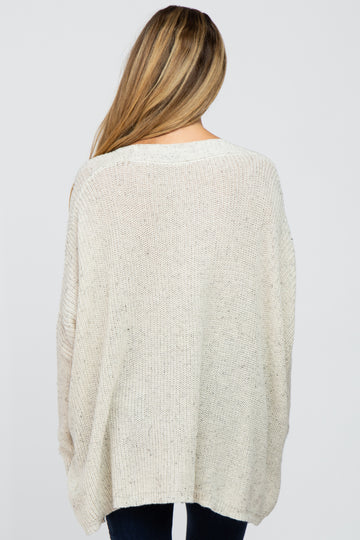 woman wearing a cream oversized maternity knit sweater, showing the back view with a relaxed fit