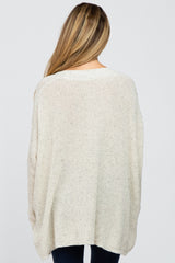 woman wearing a cream oversized maternity knit sweater, showing the back view with a relaxed fit
