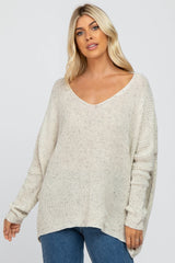 woman wearing a cream oversized v-neck knit sweater with long sleeves and a relaxed fit