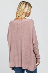 woman wearing a light pink oversized knit sweater from the back, paired with blue jeans