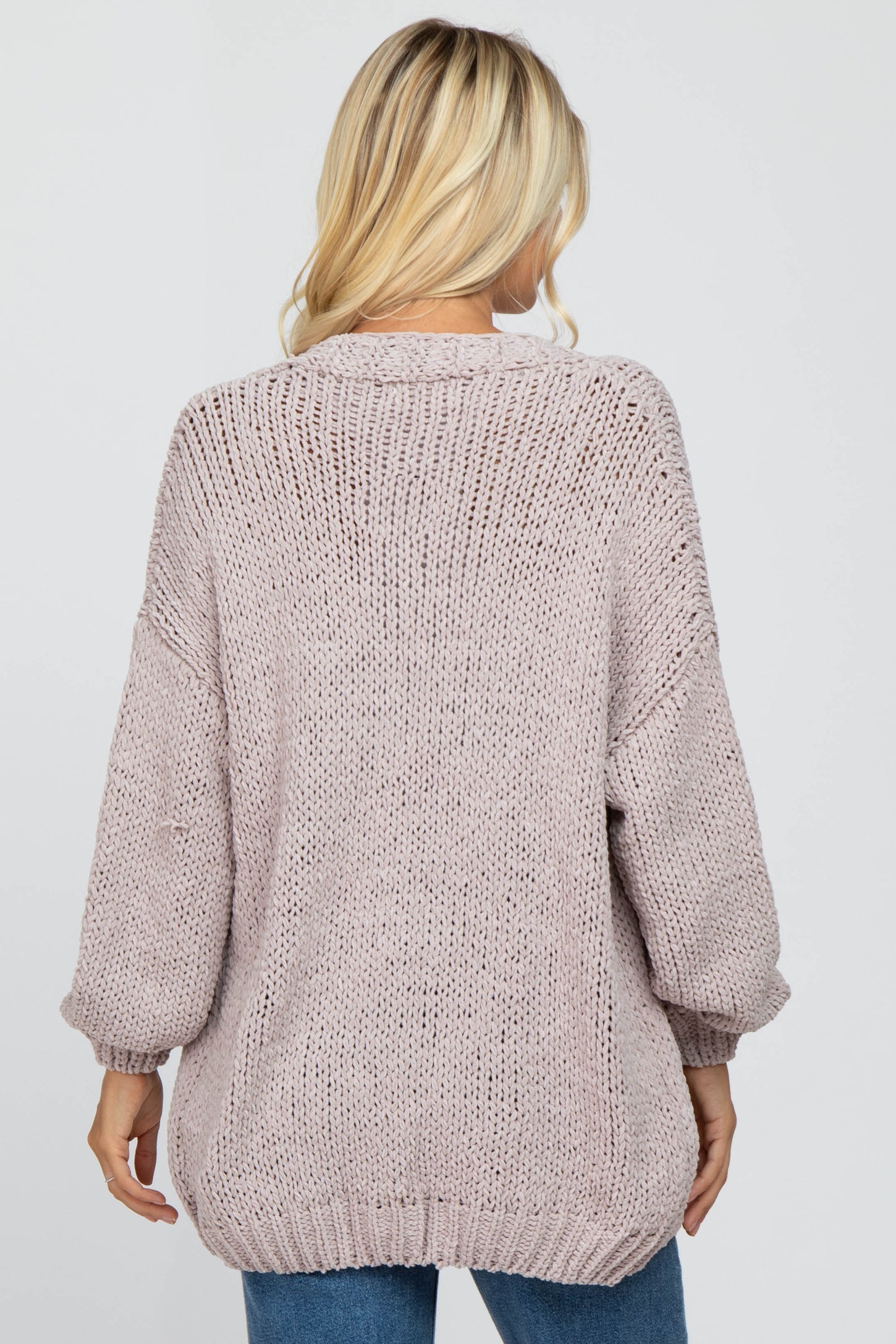 woman wearing a light pink oversized knit sweater with a relaxed fit and long sleeves, view from the back