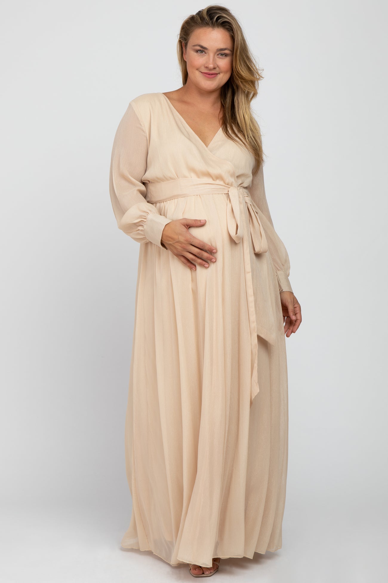 woman wearing a mauve long sleeve maternity dress with a wrap design and holding her baby bump
