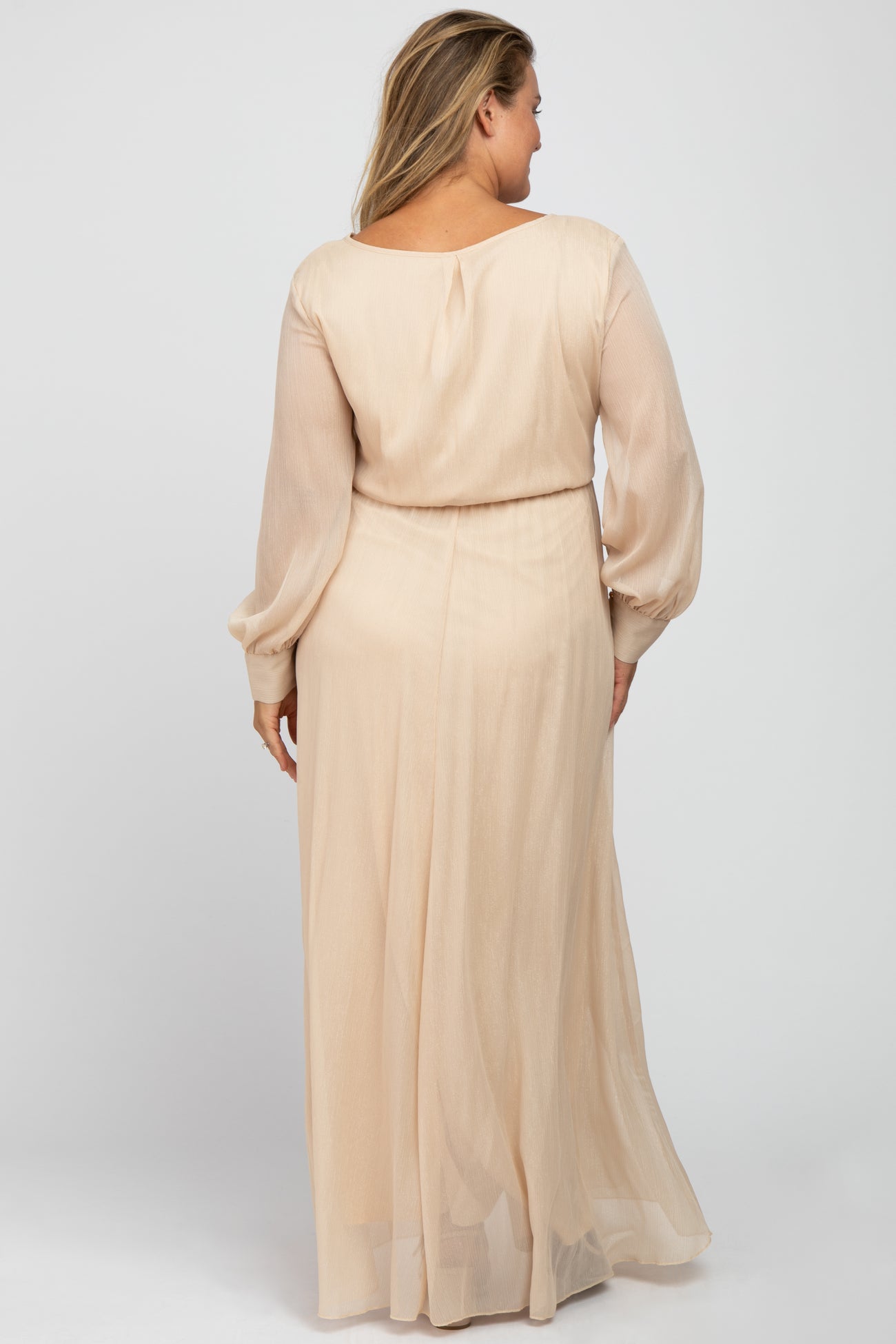 woman wearing a light beige long sleeve maternity dress with a flowy skirt, showing the back view of the garment
