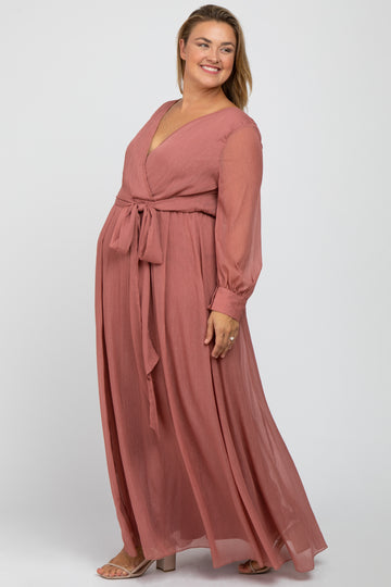 woman wearing a dusty rose floor-length maternity dress with long sleeves and a tie waist, showcasing her baby bump