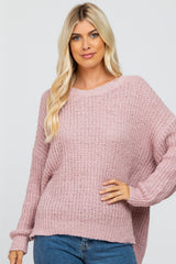 blonde woman wearing a mauve oversized popcorn knit sweater and blue jeans