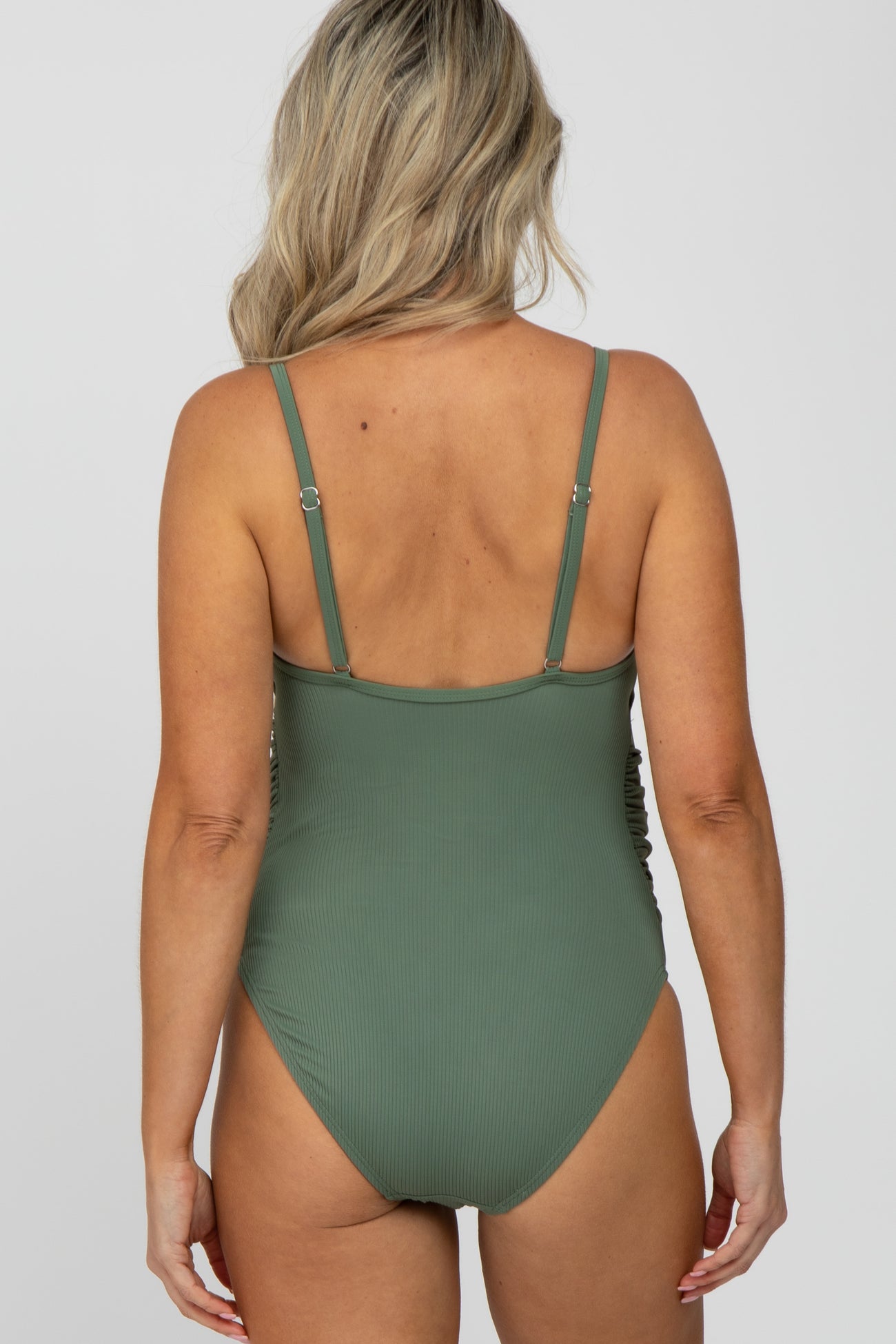 woman wearing a green maternity swimsuit with adjustable straps and a ribbed texture, showing the back view