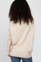 woman wearing a beige oversized sweater with a relaxed fit and long sleeves, styled with blue jeans