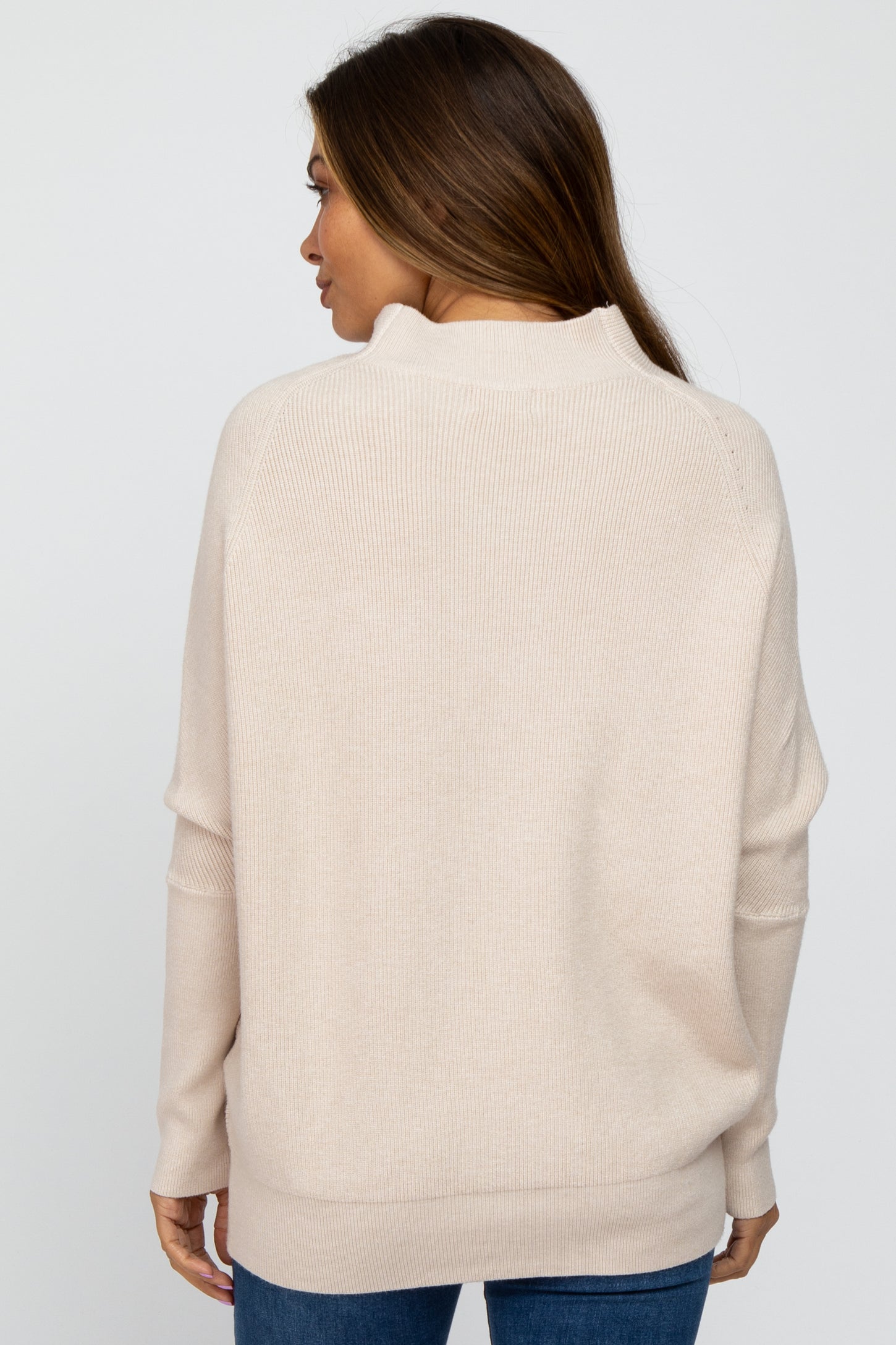 woman wearing a beige maternity sweater with a relaxed fit and ribbed texture, viewed from the back