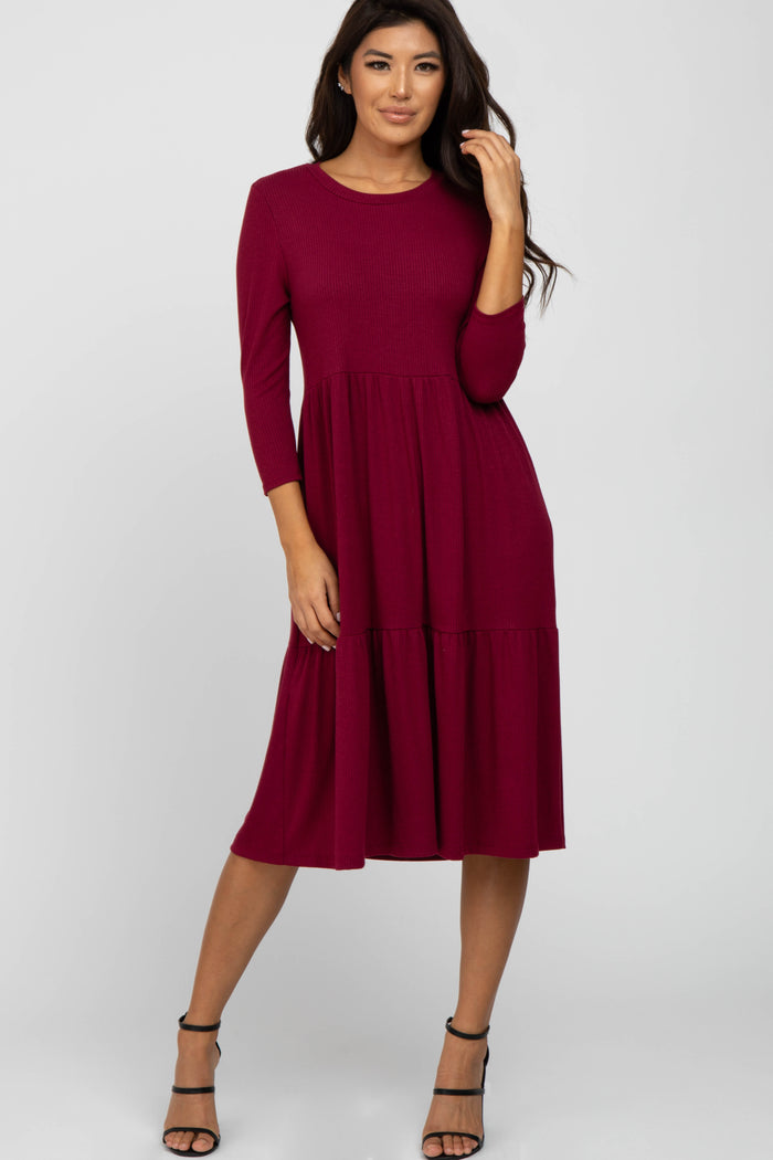 woman wearing a burgundy three-quarter sleeve midi dress with a tiered skirt and strappy black heels