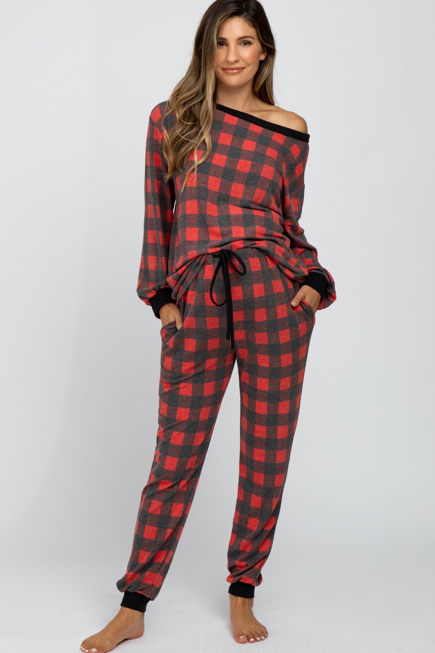 woman wearing a red and black plaid maternity pajama set with an off-the-shoulder top and pants