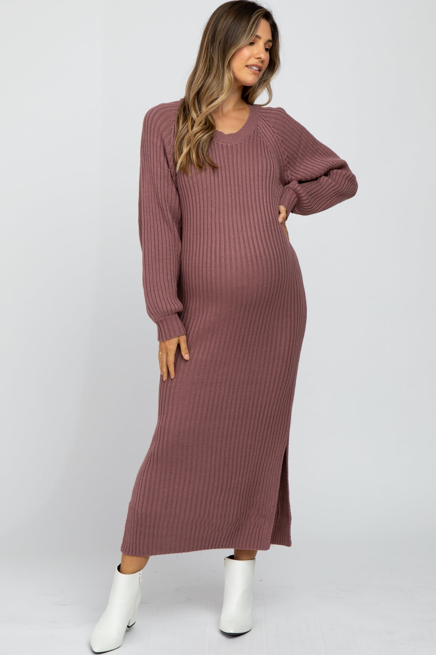 woman wearing a dusty mauve ribbed maternity dress with long sleeves and side slit, showcasing her baby bump
