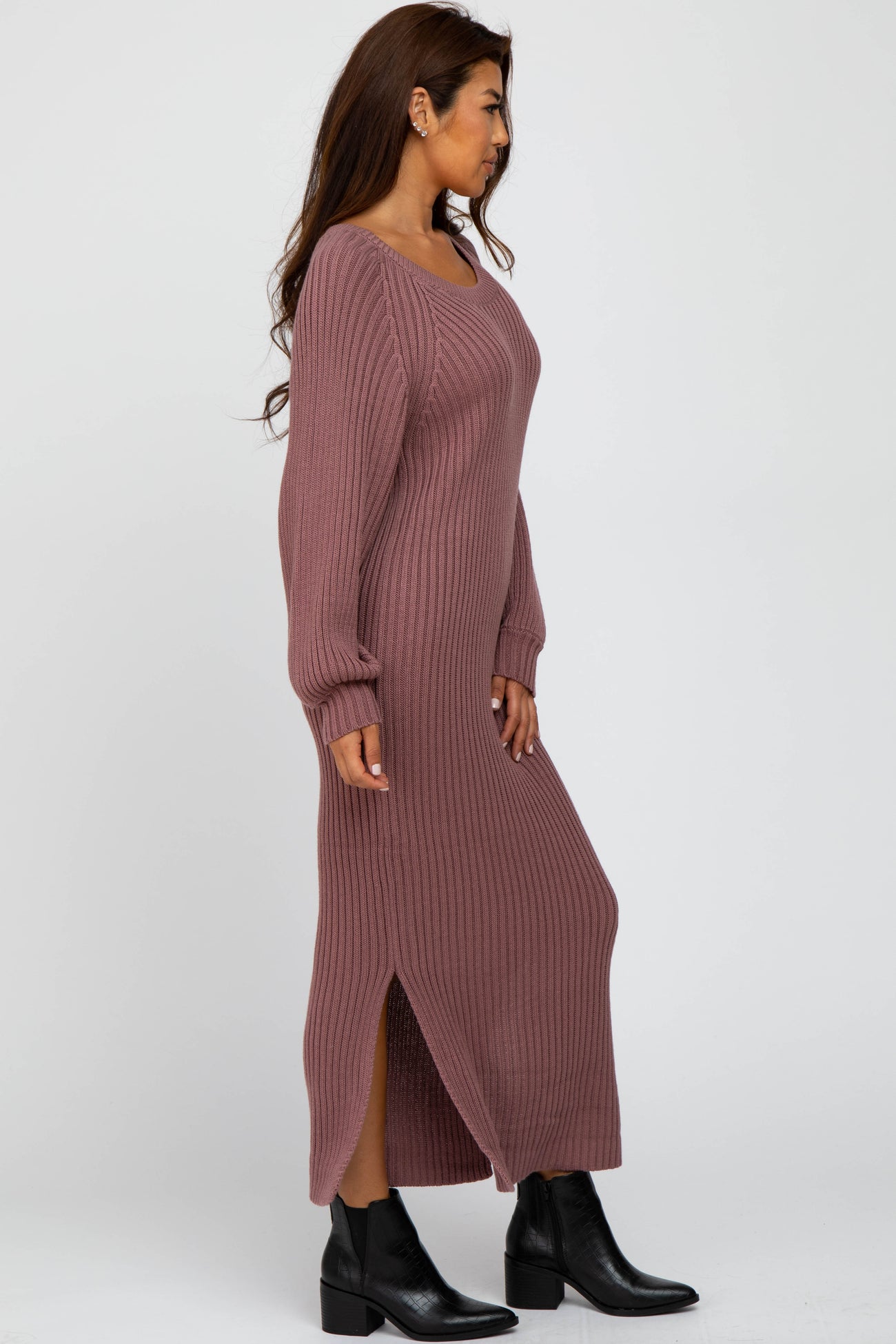 woman wearing a long mauve ribbed sweater dress with side slits and long sleeves, paired with black ankle boots
