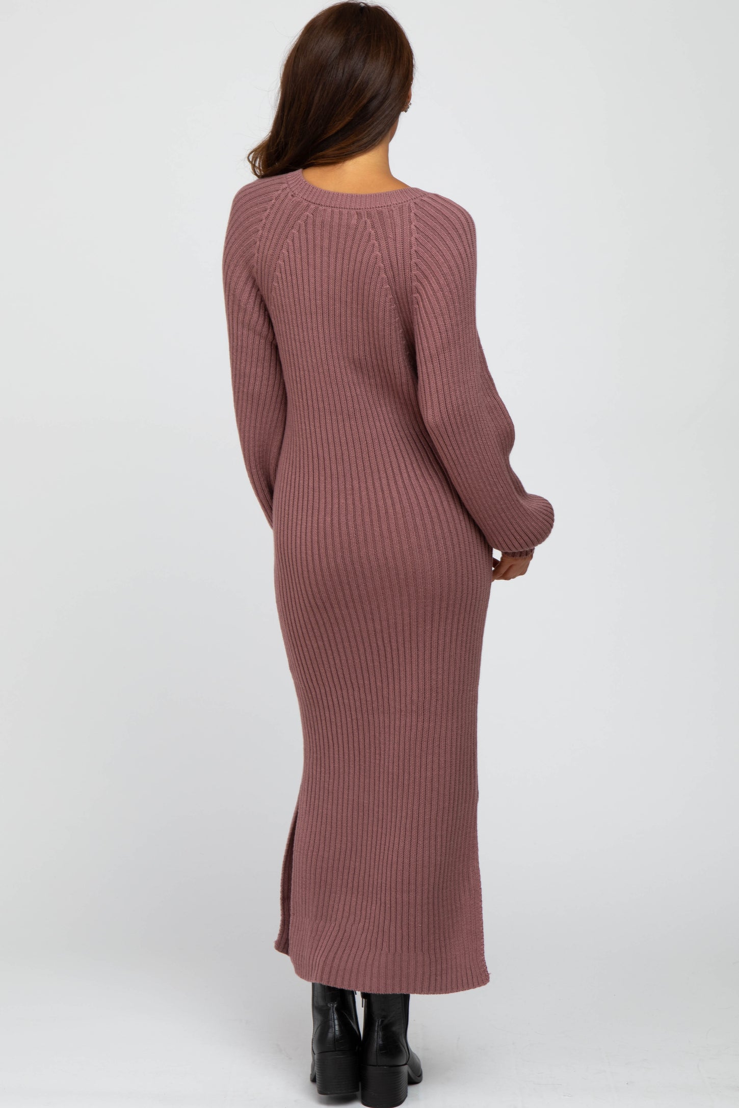 woman wearing a long mauve ribbed knit dress with a fitted silhouette and side slits