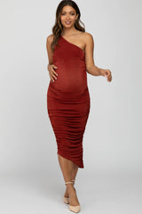 woman wearing a rust one-shoulder maternity dress with ruching and a visible baby bump