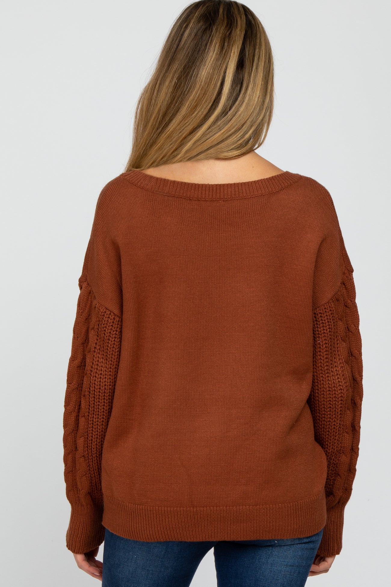 woman wearing a brown off-the-shoulder maternity sweater with textured sleeves and a relaxed fit