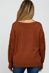 woman wearing a brown off-the-shoulder maternity sweater with textured sleeves and a relaxed fit