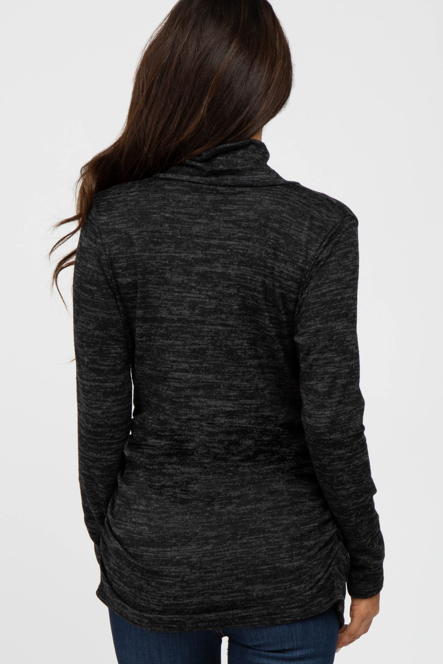 woman wearing a black marled long sleeve top with a cowl neck and ruching detail at the waist