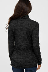 woman wearing a black marled long sleeve top with a cowl neck and ruching detail at the waist