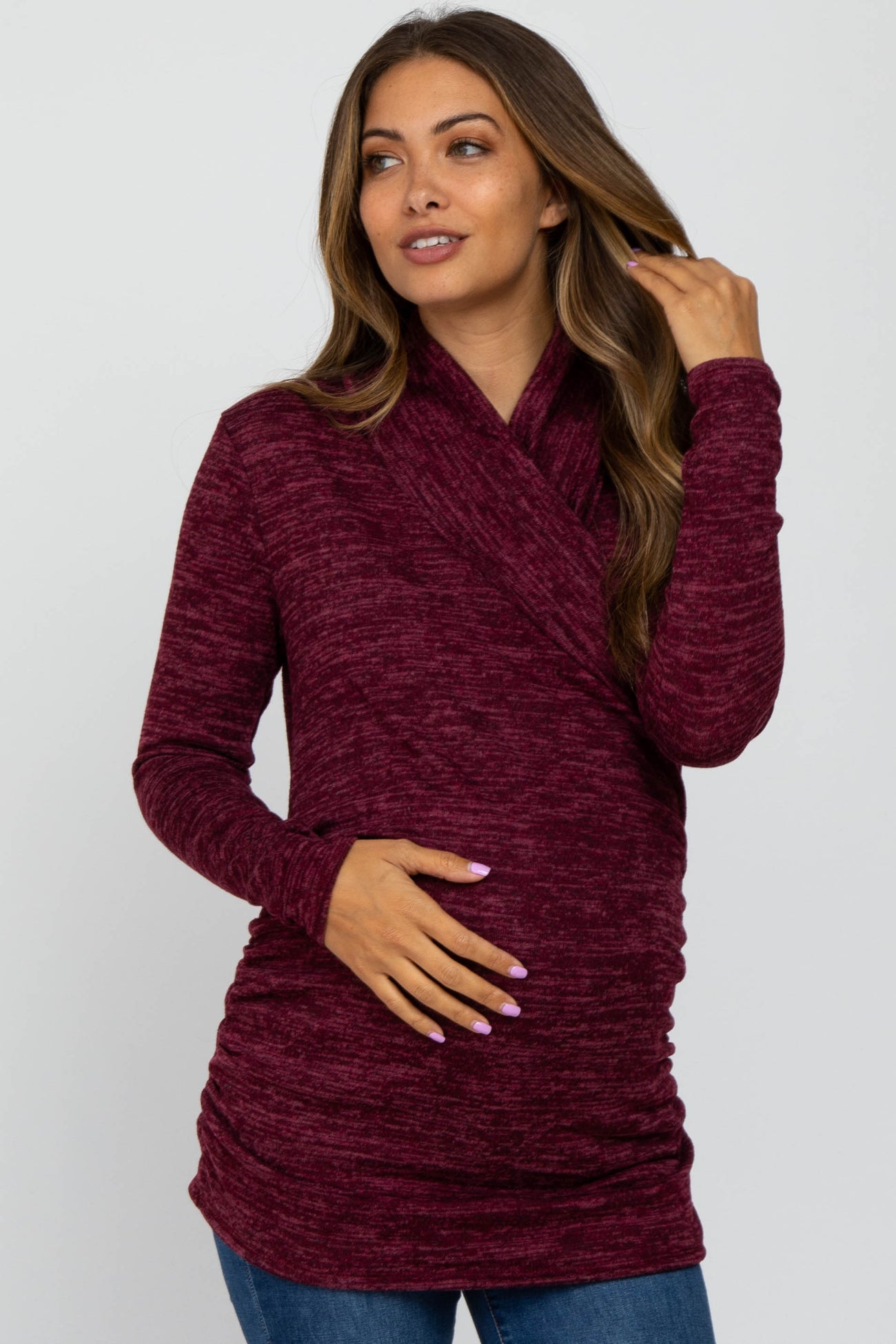 woman wearing a burgundy long sleeve maternity top with a wrap design and a visible baby bump