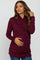 woman wearing a burgundy long sleeve maternity top with a wrap design and a visible baby bump