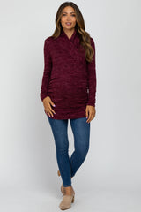 woman wearing a burgundy long sleeve maternity wrap top with a baby bump and paired with skinny jeans