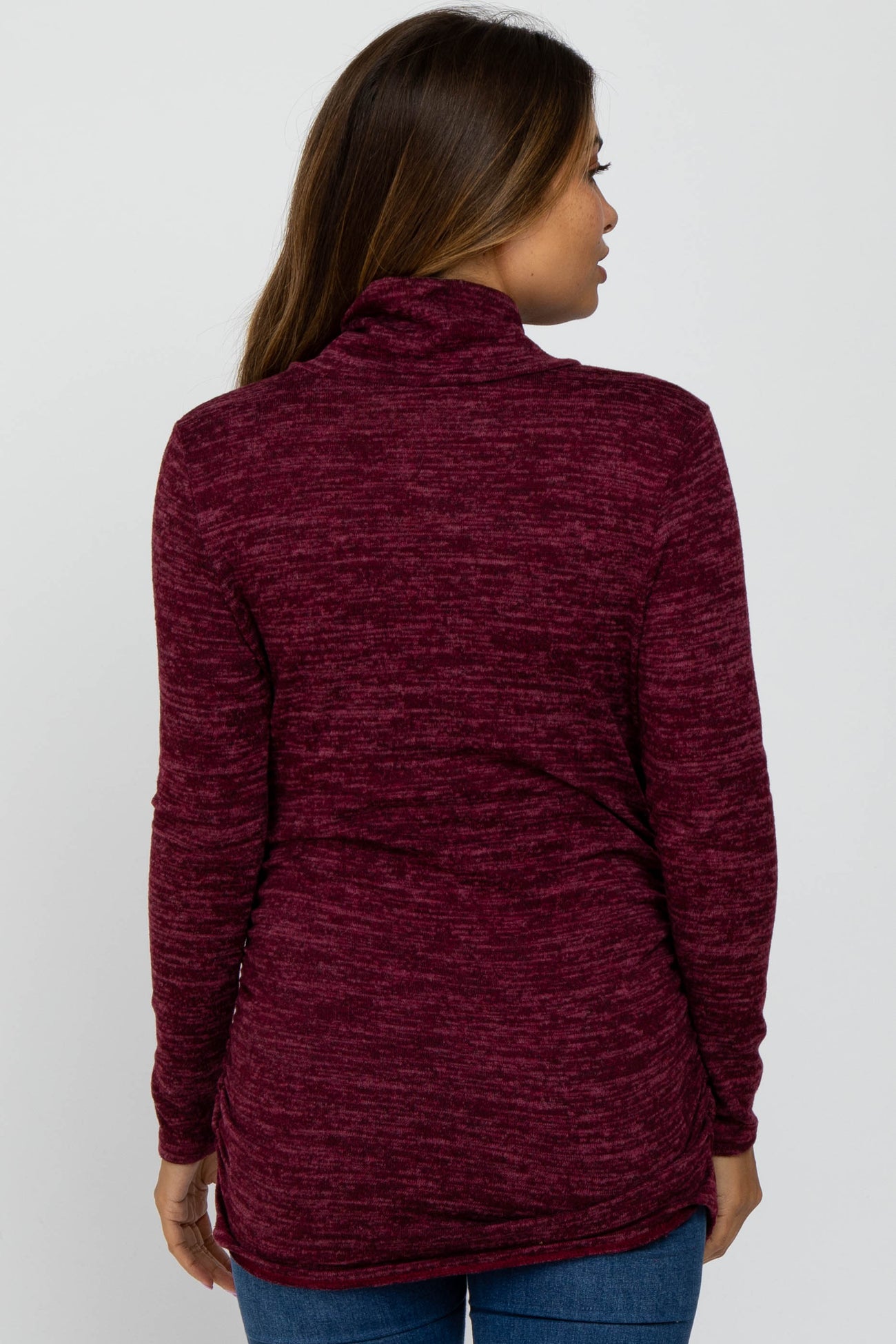 woman wearing a burgundy long sleeve maternity sweater with a cowl neck and side ruching