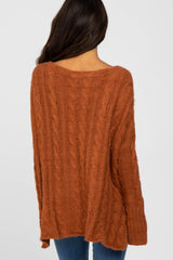 woman wearing an oversized rust cable knit sweater from the back, paired with blue jeans